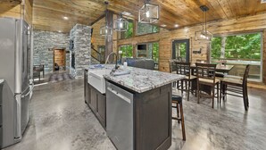 A spacious kitchen with a large island, stone accents, and wooden beams.