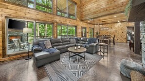 A spacious living area with a large sectional sofa, a round coffee table, and a patterned rug.