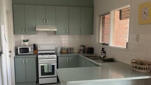 Una cucina moderna con mobili verdi, un'isola centrale con sgabelli, un forno a microonde, un forno e un lavello.