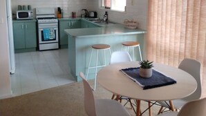 Una cucina moderna con mobili verdi, un'isola centrale e un'area pranzo con tavolo e sedie.