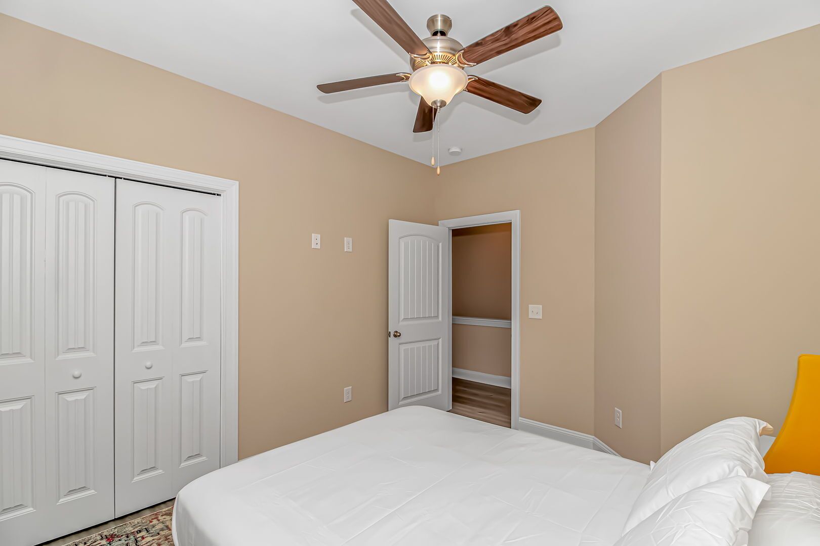 A bedroom with a bed, a wardrobe, a closet, and a ceiling fan.