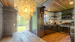 Eine moderne Küche mit Holzboden, Edelstahlgeräten und einem großen Esstisch aus Holz.