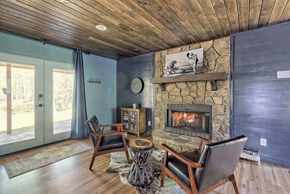 A cozy living room with a stone fireplace, leather chairs, and a large window.