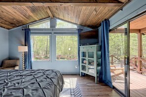 Un dormitorio con una cama grande, televisión y vistas a una terraza de madera.