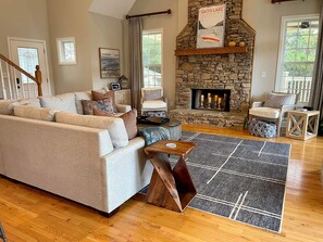 A cozy living room with a stone fireplace, a sofa, and a coffee table. - Clearwater Shores-Waterfront Stunning Views-Smith Lake, AL-5 Bedrooms-Near I-65 (Bremen)