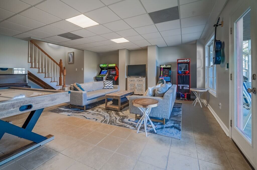 A spacious living area with a pool table, sofas, and arcade games.