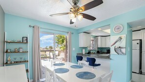 A bright kitchen with white cabinets, a ceiling fan, and a dining area with a table and chairs.