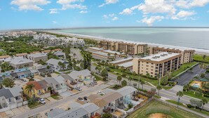 A coastal residential area with multiple-story buildings, a beach, and a clear sky.