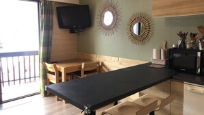A modern kitchen with a black countertop, wooden chairs, and a television mounted on the wall. - Studio cabin   4 People  Resort center   Parking (VALLOIRE)