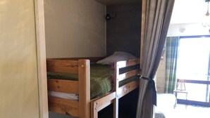 A bunk bed room with a wooden frame, a green mattress, and a white pillow. There is a window with curtains and a chair outside. - Studio cabin   4 People  Resort center   Parking (VALLOIRE)
