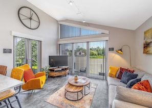 A modern living room with a TV, sofa, chairs, and a dining area.