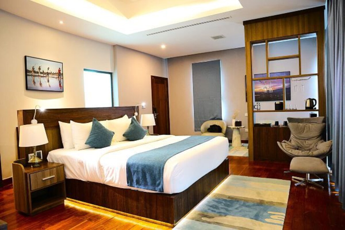 A modern hotel room with a large bed, bedside tables, a desk, and a chair.