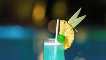 A cocktail with a straw, pineapple slice, and cherry garnish on a table.