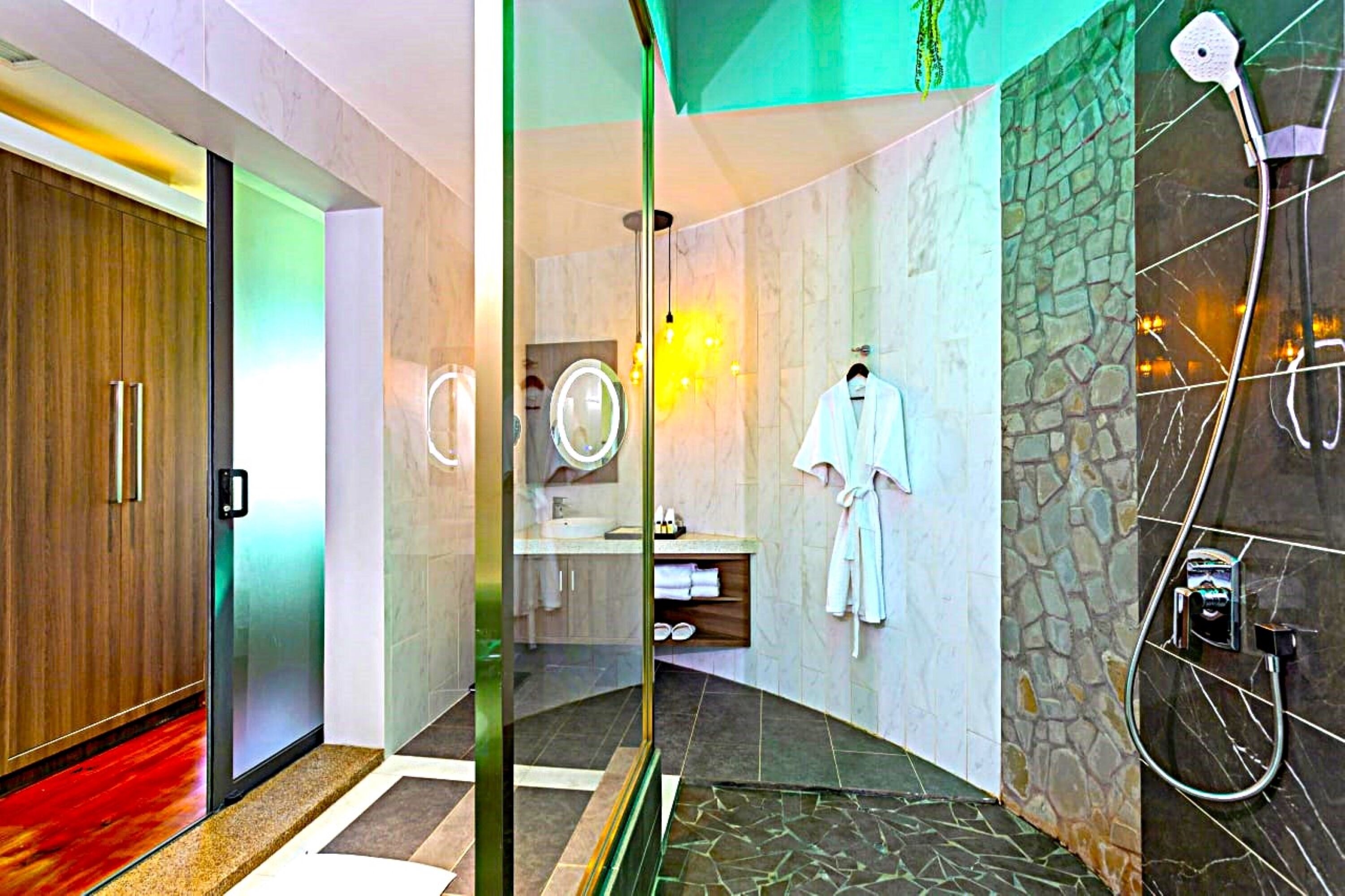 A modern bathroom with a glass partition, a shower area, and a robe hanging on the wall.