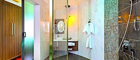 A modern bathroom with a glass partition, a shower area, and a robe hanging on the wall.