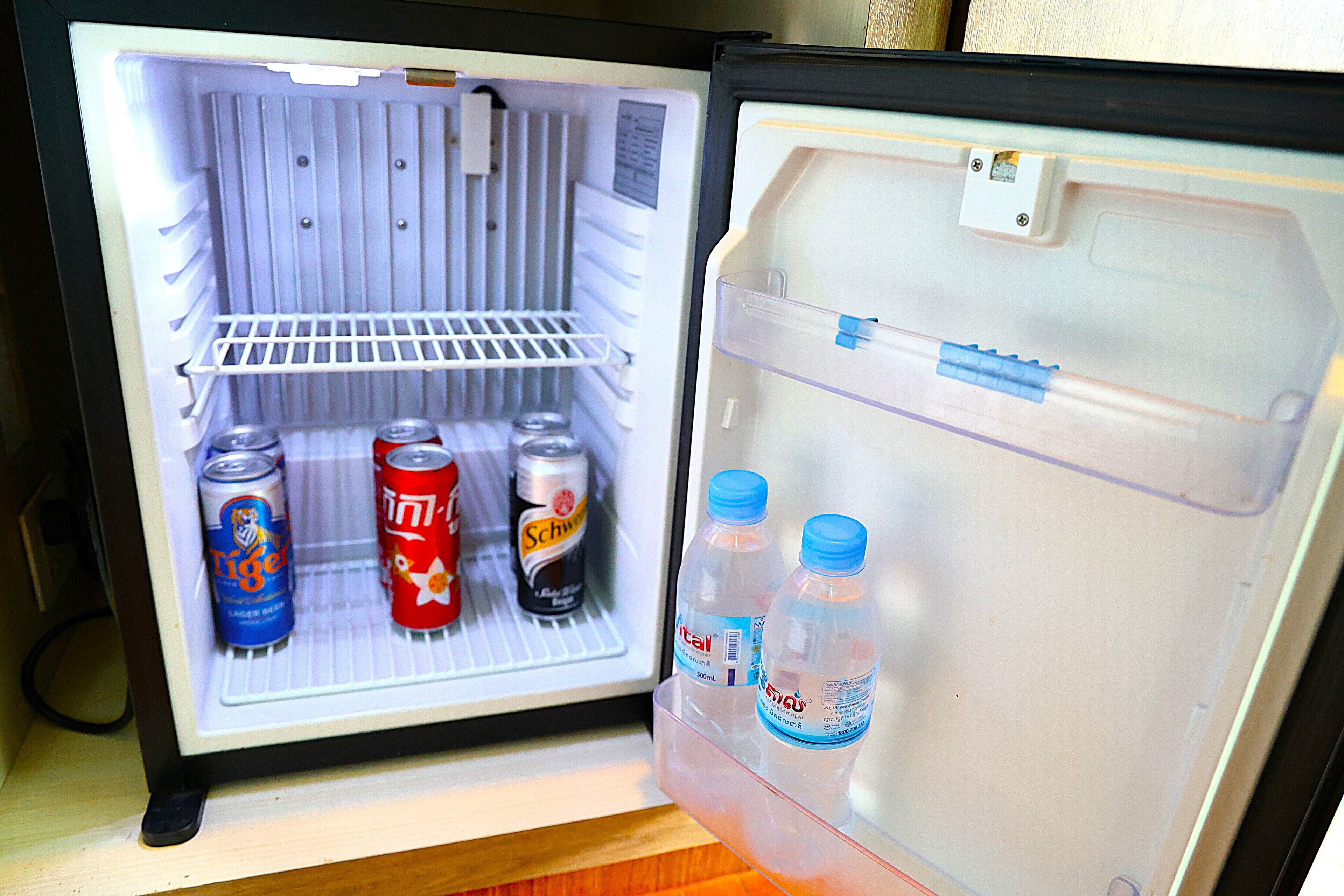 A refrigerator with shelves containing beverages and cans.