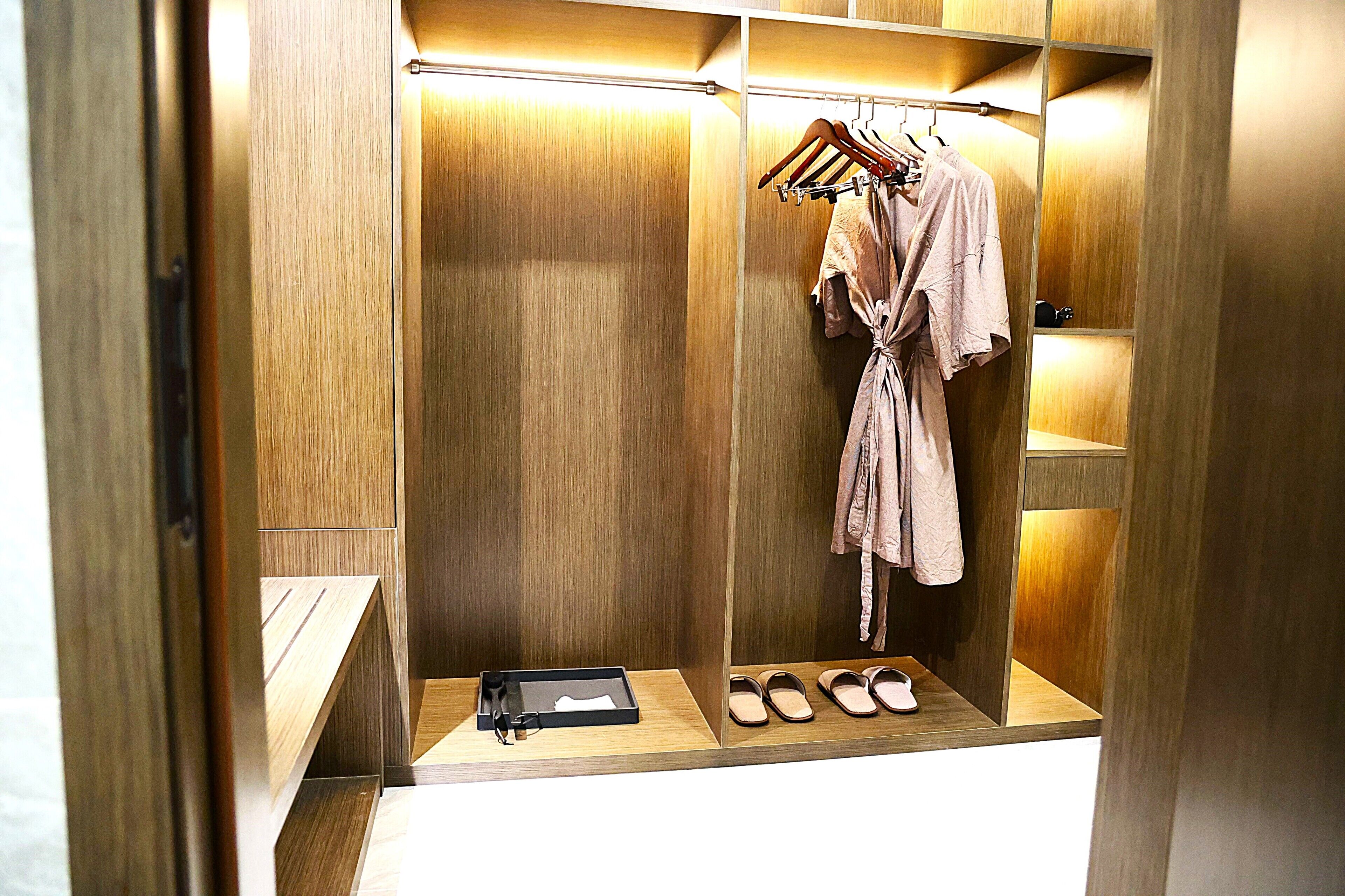 A walk-in closet with wooden paneling, a robe hanging on a rack, and a pair of shoes on the floor.
