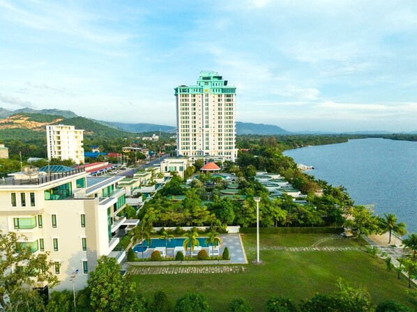 A high-rise hotel with a swimming pool and lush greenery.