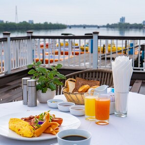 A breakfast table with a view of a marina, including boats and buildings in the background.