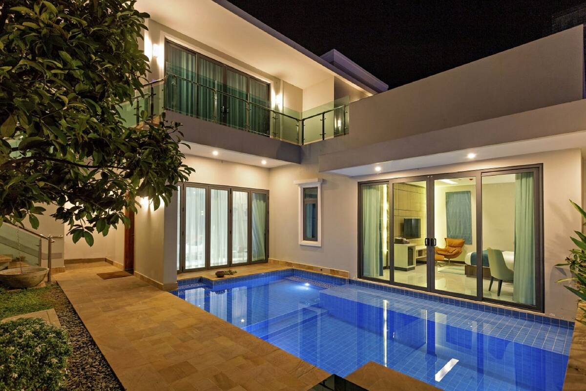 Una casa moderna de dos pisos con piscina, ventanas amplias y un balcón.