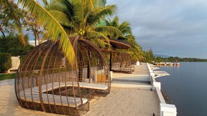 Zona de playa con cabañas de mimbre y palmeras.