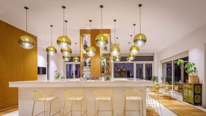 Une cuisine moderne dotée d’un îlot central, de tabourets de bar, de luminaires suspendus et offrant une vue sur l’espace de vie.