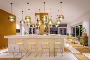 Uma cozinha moderna com uma ilha central, banquetas, iluminação pendente e vista para a sala de estar.