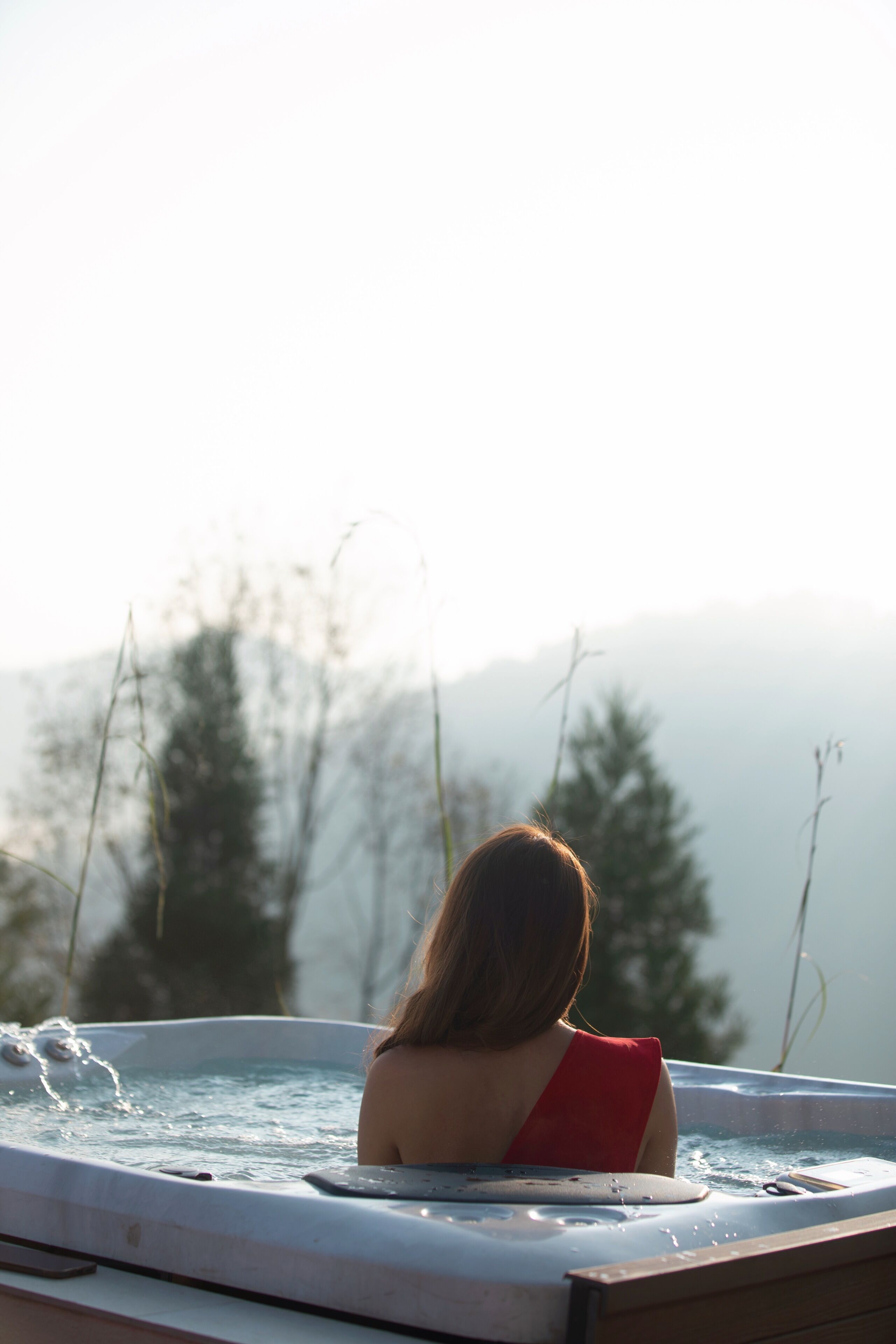 A person sitting in a hot tub with a view of mountains in the background.
