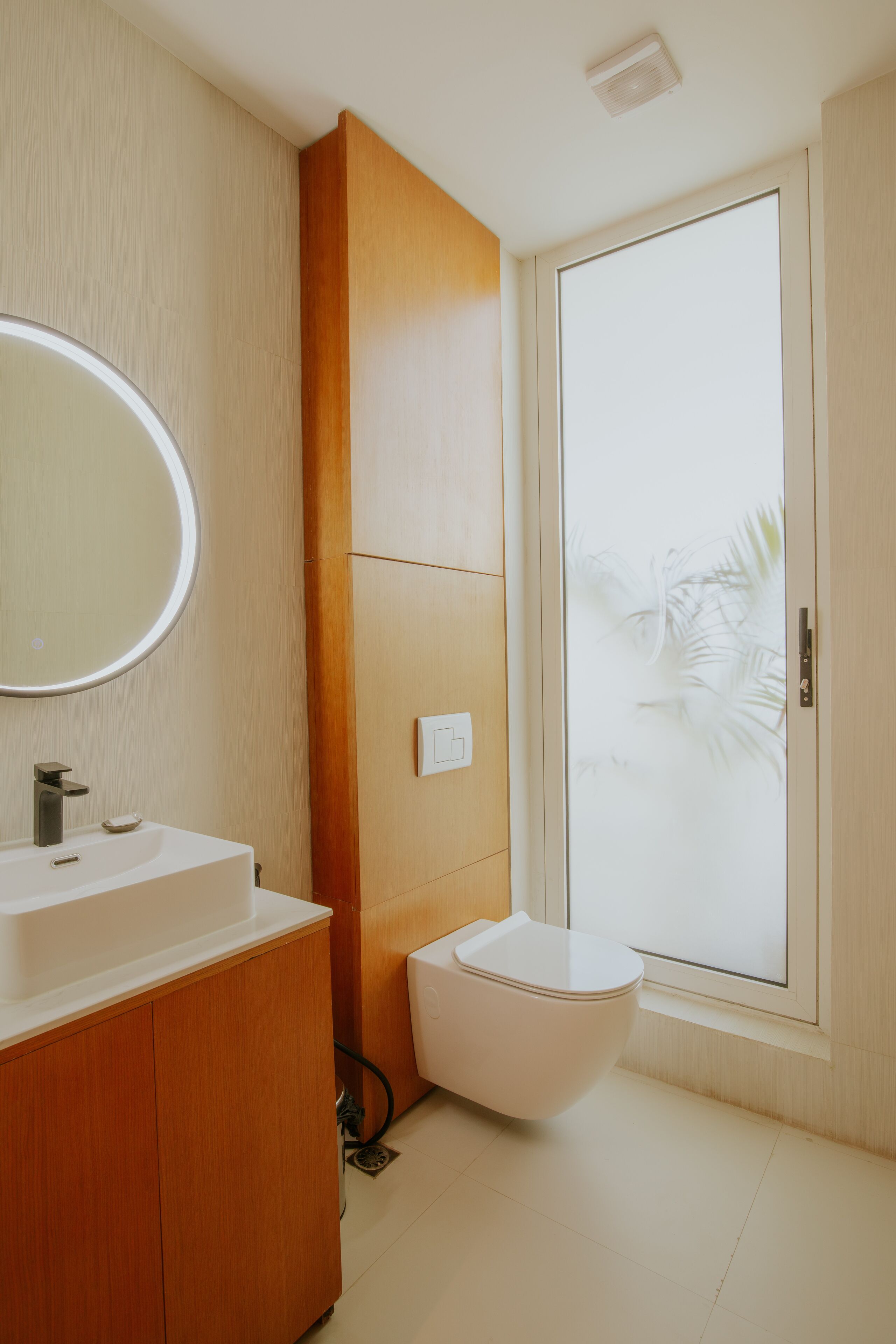 A modern bathroom with a white sink, wooden vanity, and a toilet.