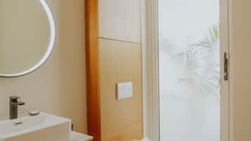 A modern bathroom with a white sink, wooden vanity, and a toilet.
