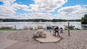 Un espace de pique-nique au bord du lac, équipé d’un barbecue, d’une table de pique-nique et de bancs.