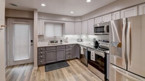 A modern kitchen with grey cabinets, stainless steel appliances, and a wooden floor. - Lakefront Luxury 212 · Lakefront Luxury for Families or Couples (Wisconsin Dells)