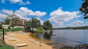 Une plage avec des chaises longues et vue sur un lac.