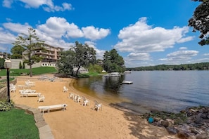 Ein Strand mit Liegestühlen und Blick auf einen See.