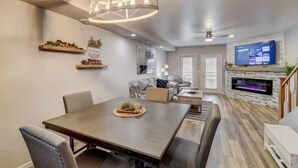 A modern living room with a dining area, a fireplace, and a TV mounted on the wall. - Lakefront Luxury 212 · Lakefront Luxury for Families or Couples (Wisconsin Dells)