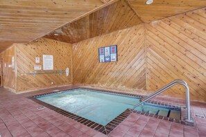 A hot tub in a wooden room with tiled flooring and a metal ladder.