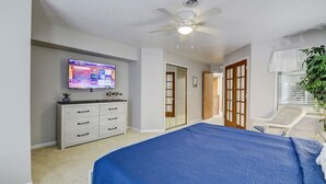 A bedroom with a large bed, a TV on the wall, a ceiling fan, and a door leading to another room. - Lakefront Luxury 212 · Lakefront Luxury for Families or Couples (Wisconsin Dells)