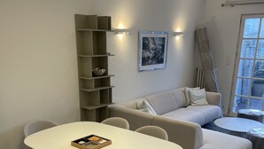 Una sala de estar moderna con un sofá blanco, una mesa de comedor con sillas y una unidad de estanterías empotradas.