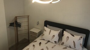 Une chambre à coucher comprenant un lit, une table de chevet, une armoire en bois et un luminaire au plafond original.