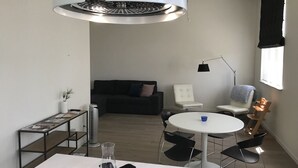 Un espace de vie moderne et compact, comprenant une table centrale, des chaises, un canapé et un radiateur portatif.