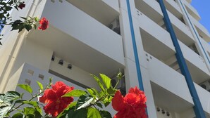 A multi-story building with balconies and a clear blue sky. - PRIME TREE Izumizaki CONDO HOTEL (Naha)