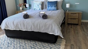 A bedroom with a bed, pillows, a nightstand, a mirror, and a painting on the wall. - Peaceful -Local Wine & Tamar River Views/Pets Allowed (Clarence Point)
