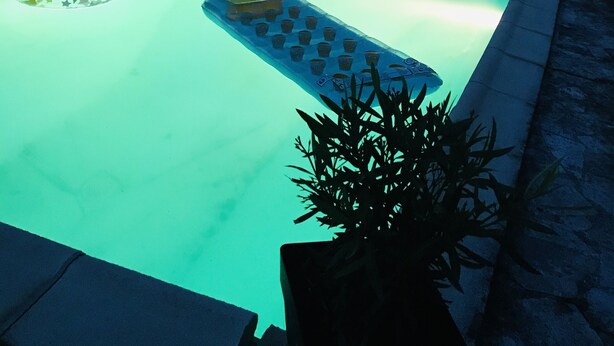 Una piscina con sillas de descanso y una mesa de billar flotante.