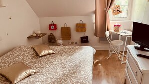 Un dormitorio con una cama grande, un escritorio, un televisor y varios objetos decorativos en la pared.