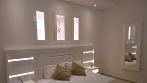 Ein modernes Schlafzimmer mit einem großen Bett, Nachttischen und einem Spiegel.