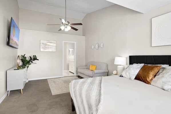 A bedroom with a bed, bedside table, lamp, and a ceiling fan.