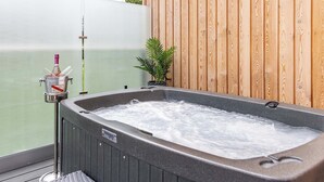 A hot tub with a wooden wall and a potted plant beside it. - Water Lily Lakeside Lodge (Boston)