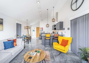 A modern living room with a sofa, coffee table, and a bright yellow chair. - Water Lily Lakeside Lodge (Boston)