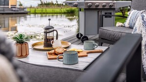 A cozy outdoor seating area with a grill, a coffee pot, and a tray with bread and cookies. - Water Lily Lakeside Lodge (Boston)