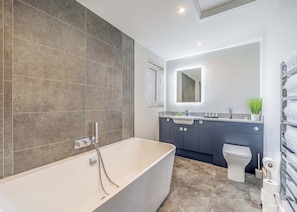 A modern bathroom with a freestanding bathtub, a toilet, and a vanity with a mirror. - Peacock Lakeside Lodge (Boston)